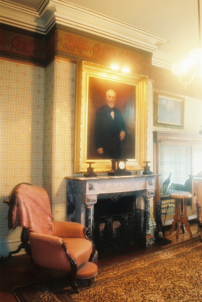 Library of Asahel Bush House Museum showing 1880 William Cogswell portrait of Asahel Bush II hanging above original marble fireplace.