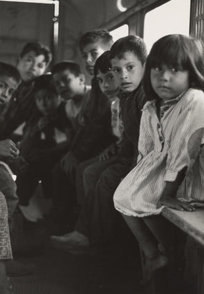 A group of children sit on wooden boards in the back of a bus that transported them and their families from Texas to Oregon for work.