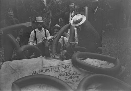 Faussett can be seen with his head protruding from a specially designed craft that he would ride over the falls. A group of surrounding men hand him inner tubes to provide buoyancy to the craft.