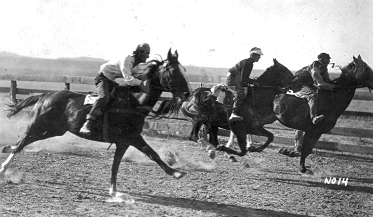 Contestants run neck and neck past the reviewing stand at the old race track during the Harney County Fair. 1900-1915 ca