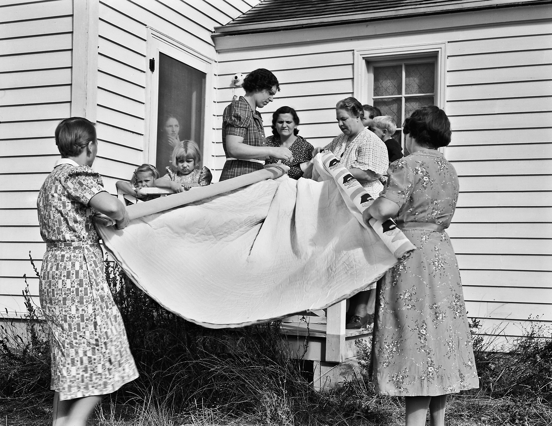 Members of the "Helping Hand" club roll up a quilt they are making, near West Carlton.