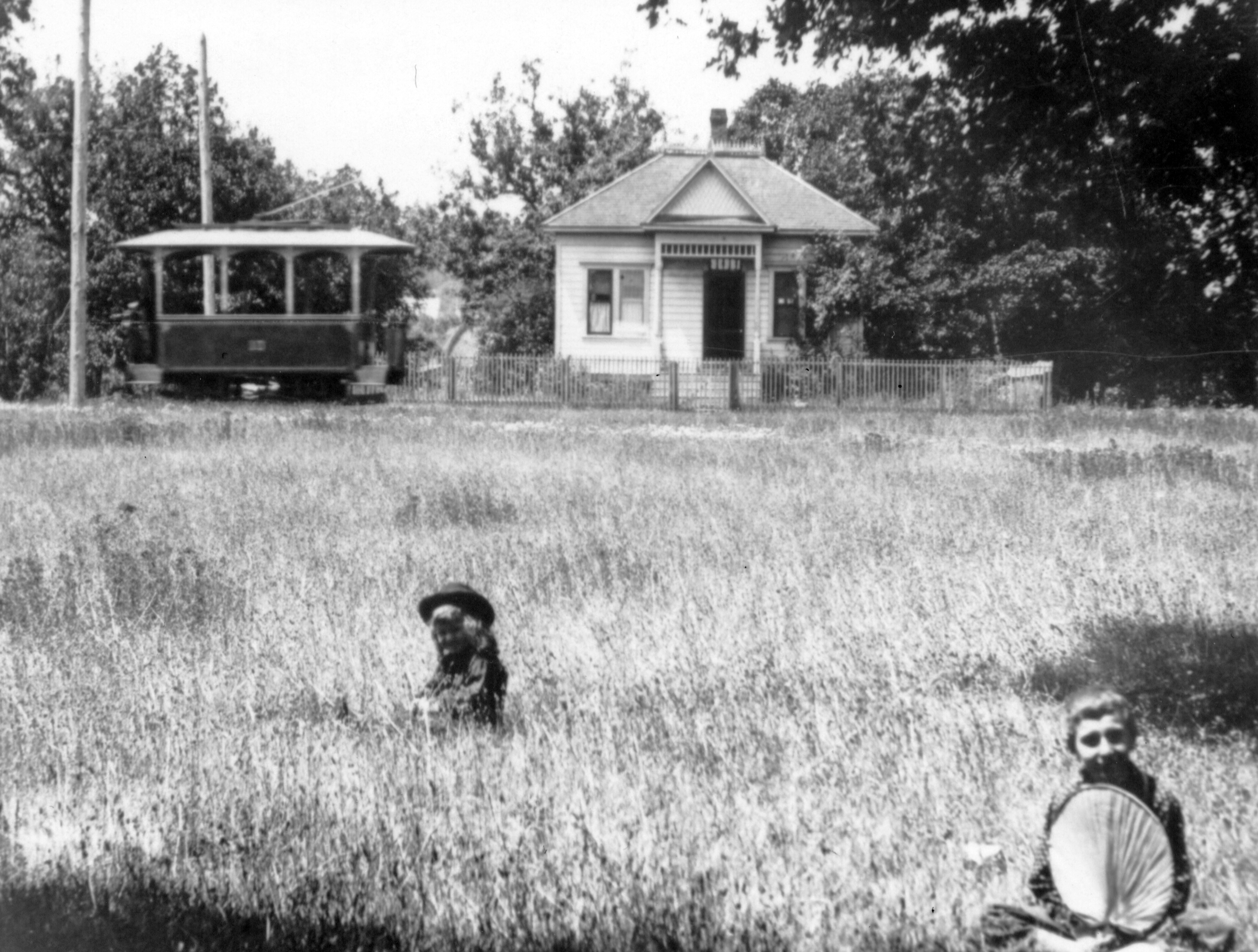 Two children in field with "Toonerville Trolley" behind, 12th and Howard Sts., Salem.