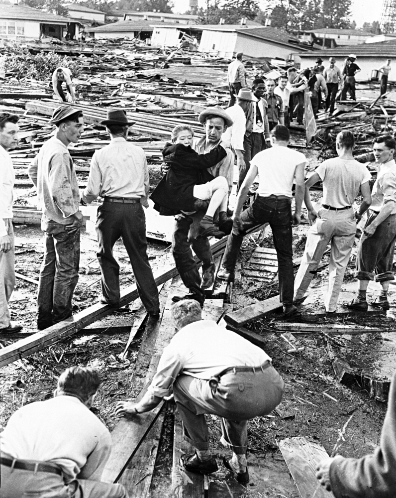 Carl Downey carries a woman to safety in aftermath of the flood, May 30, 1948.