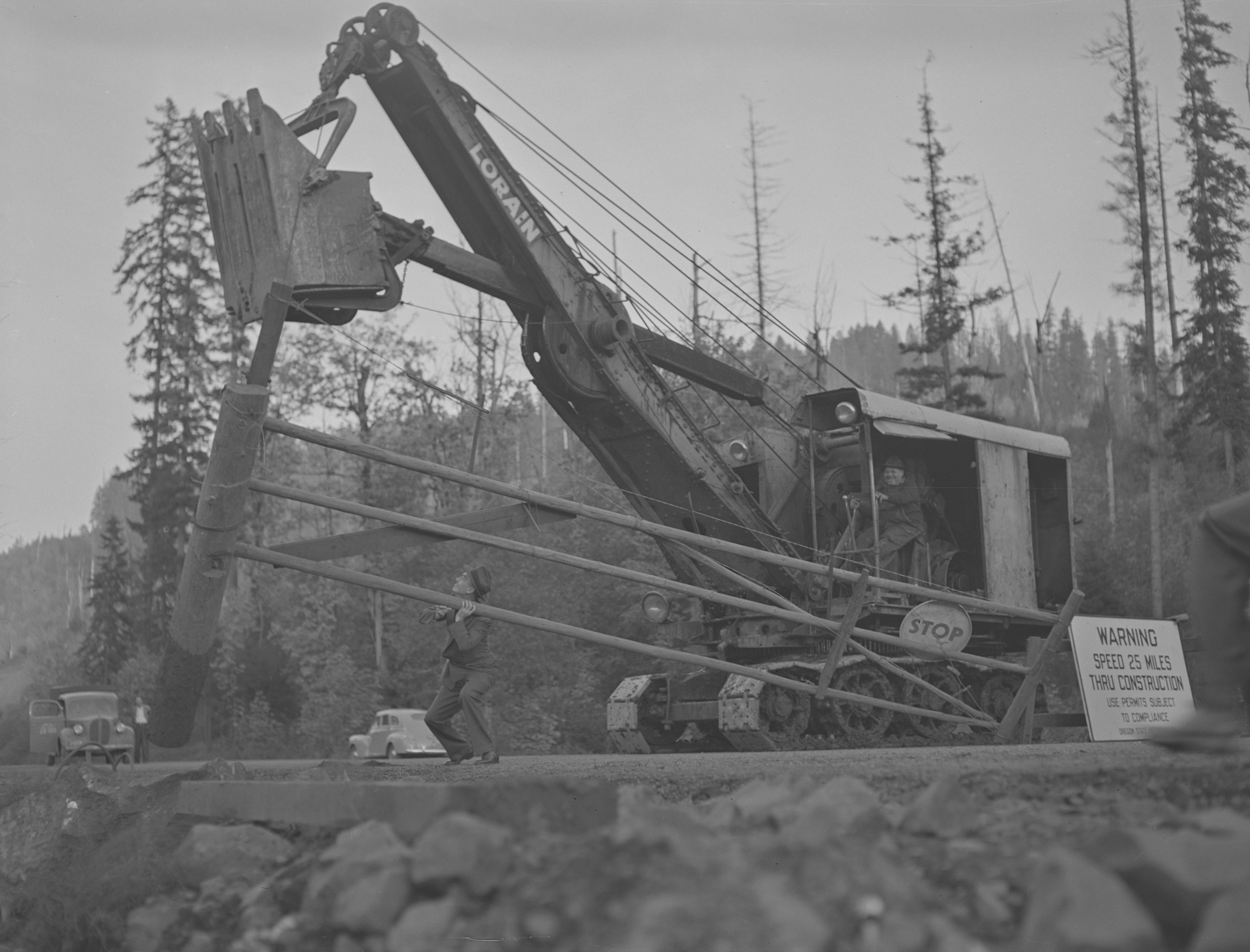 Photograph showing a gate on the newly opened Wilson River Road, being removed by a crane.