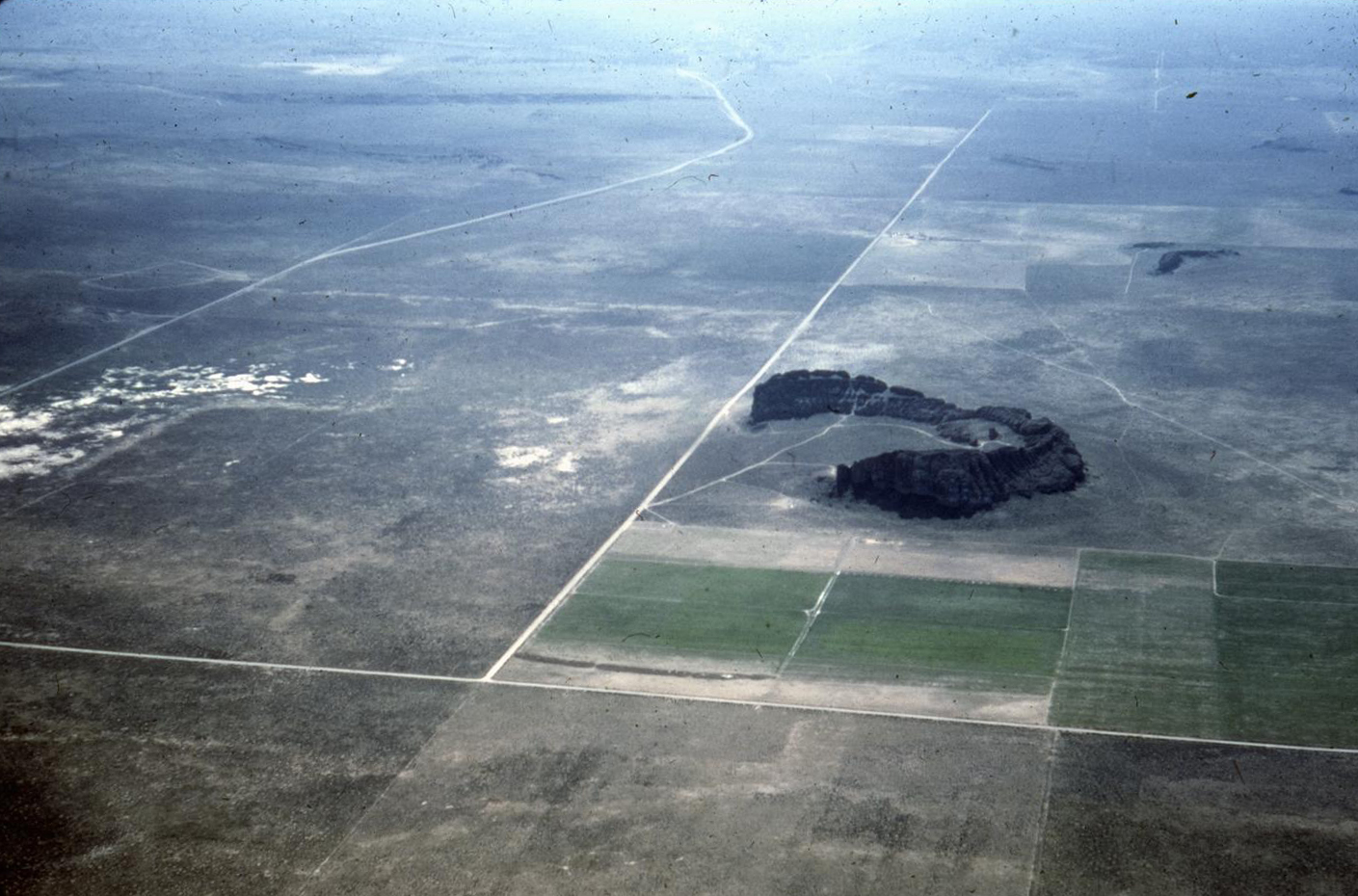Fort Rock Cave is located in rock formation slightly right and farther back in photo.