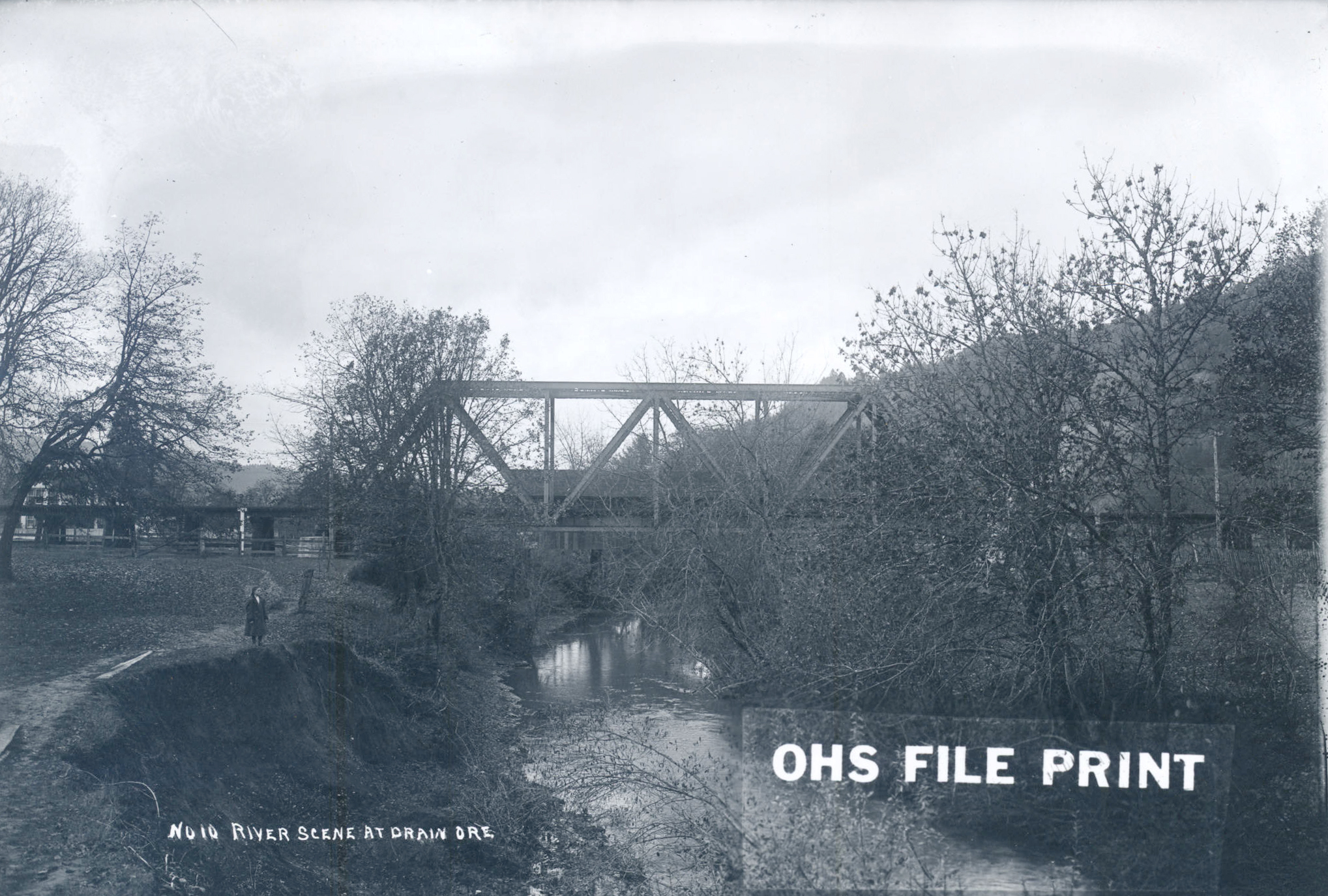 The covered bridge can be seen behind the railroad bridge in this early photo of Pass Creek